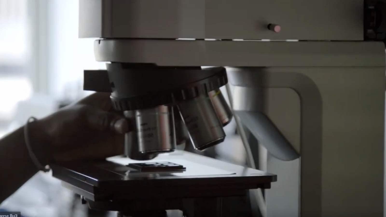 显微镜的近照和一只手定位载玻片
